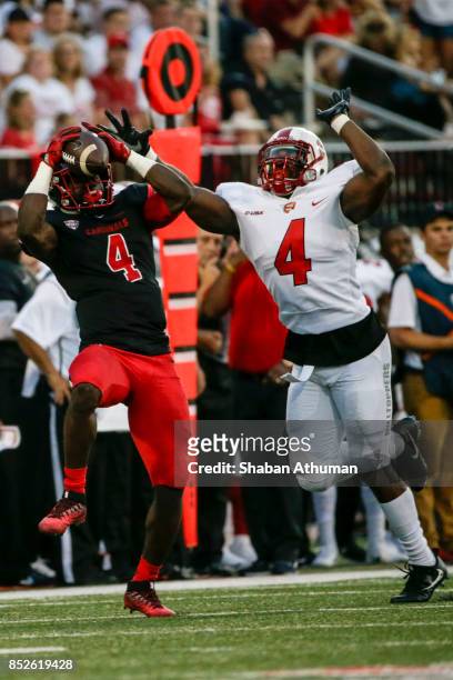 Running Back Malik Dunner of the Ball State Cardinals makes a catch against Linebacker Joel Iyiegbuniwe of the Western Kentucky Hilltoppers on...