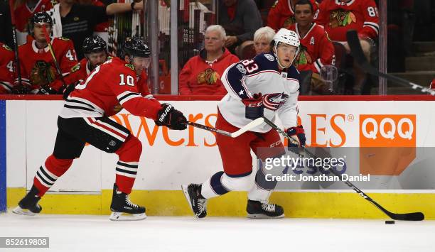 Calvin Thurkauf of the Columbus Blue Jackets looks to pass under pressure from Patrick Sharp of the Chicago Blackhawks during a preseason game at the...