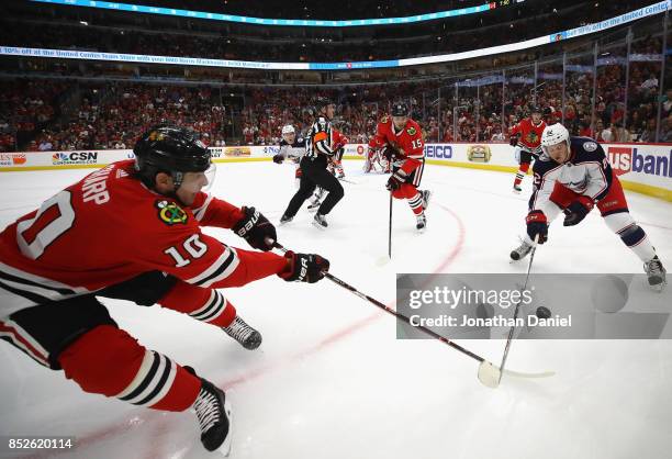Patrick Sharp of the Chicago Blackhawks knocks the puck away from Bobby MacIntyre of the Columbus Blue Jackets during a preseason game at the United...