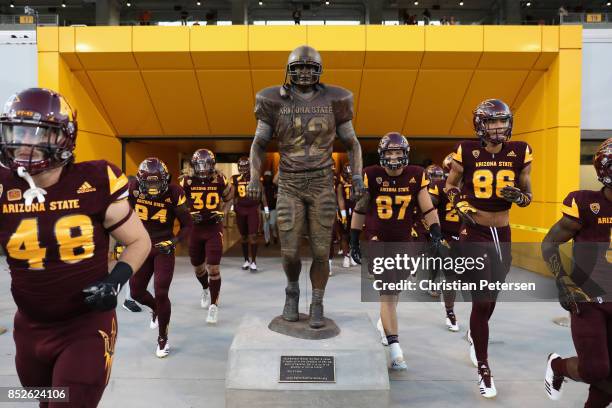 Arizona State Sun Devils players run past the Pat Tillman statue before the college football game against the Oregon Ducks at Sun Devil Stadium on...