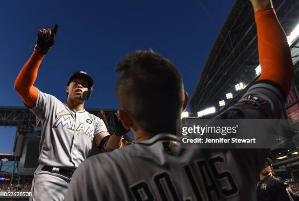 Giancarlo Stanton of the Miami Marlins celebrates in the dugout after hitting a solo home run in the fourth inning against the Arizona Diamondbacks...