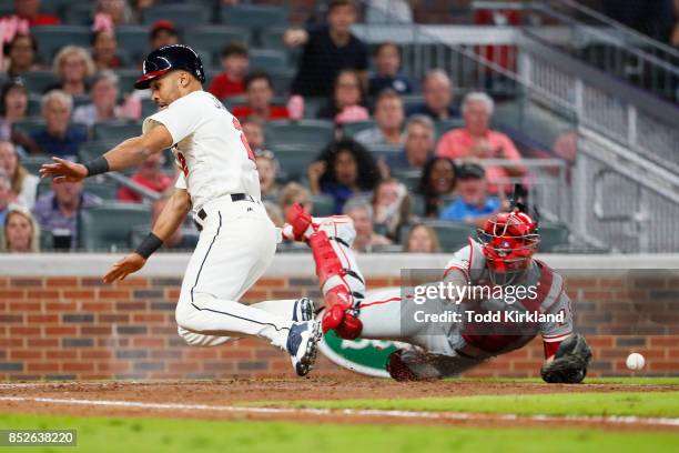 Micah Johnson of the Atlanta Braves avoids the tag of Cameron Rupp of the Philadelphia Phillies to score off a single of Dansby Swanson in the eighth...