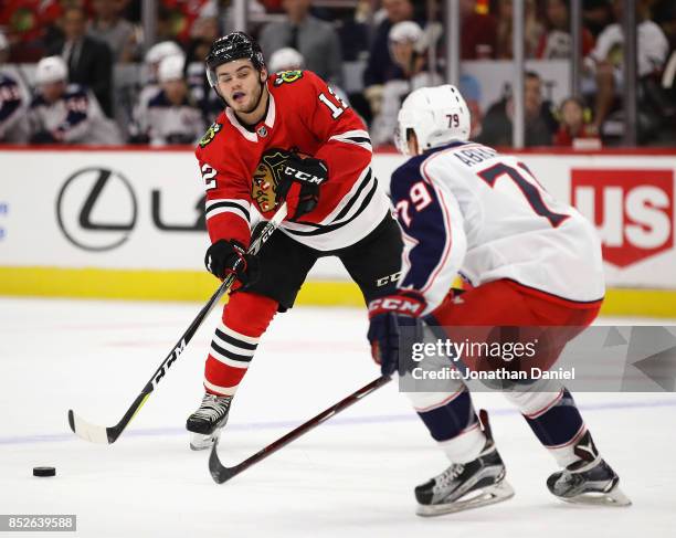 Alex DeBrincat of the Chicago Blackhawks passes arund Vitaly Abramov of the Columbus Blue Jackets during a preseason game at the United Center on...