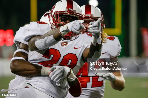 Running back Jakairi Moses of the Western Kentucky Hilltoppers celebrates with a teammates after scoring a touchdown against Ball State on September...