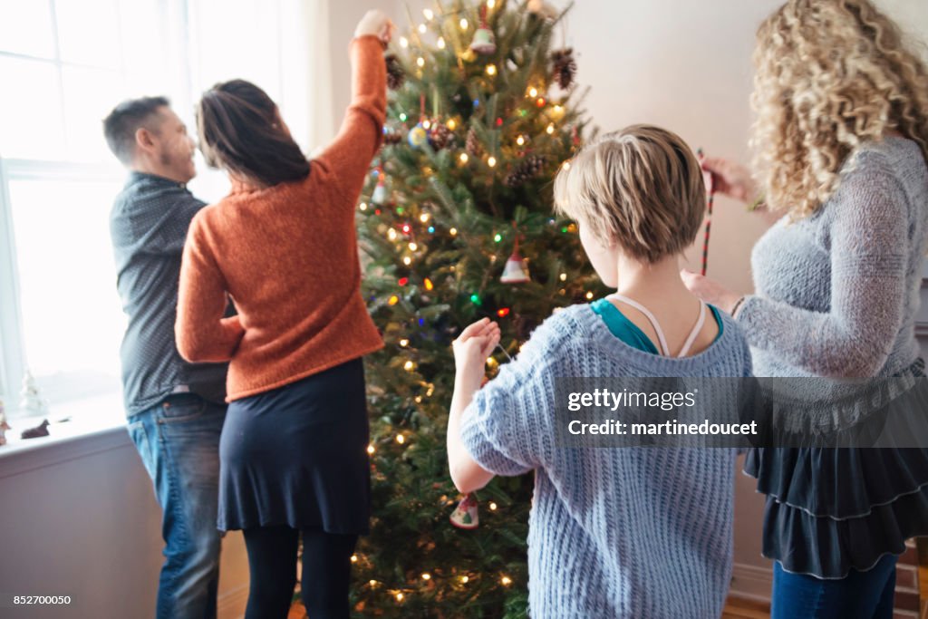 Family decorating Christmas tree at home.