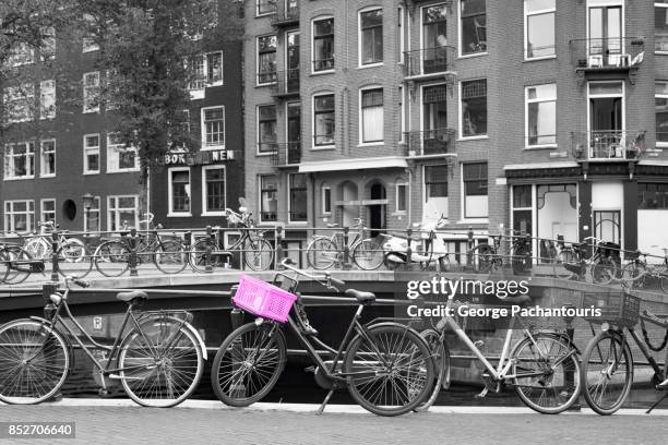 bicycle with pink basket parked on a canal in amsterdam, netherlands - isolated colour stock pictures, royalty-free photos & images