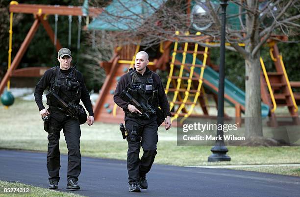 Two U.S. Secret Service agents carry machine guns as they walk past a new swing set on the south lawn of the White House on March 6, 2009 in...