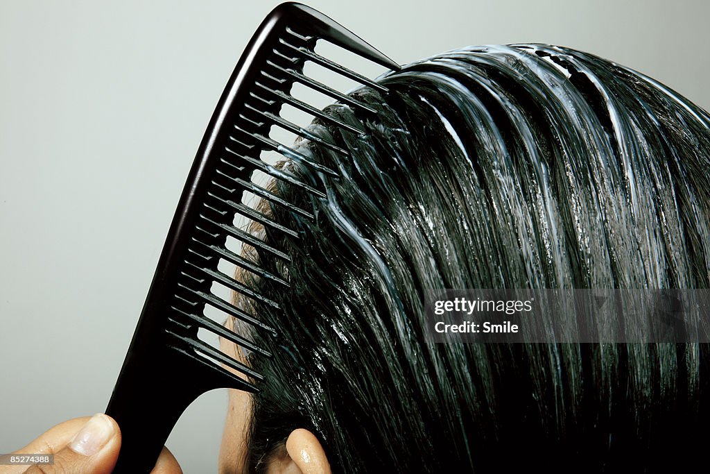 Combing conditioner through hair, close up