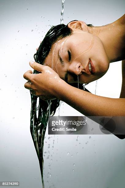 young woman rinsing hair in water - washing hair stock-fotos und bilder