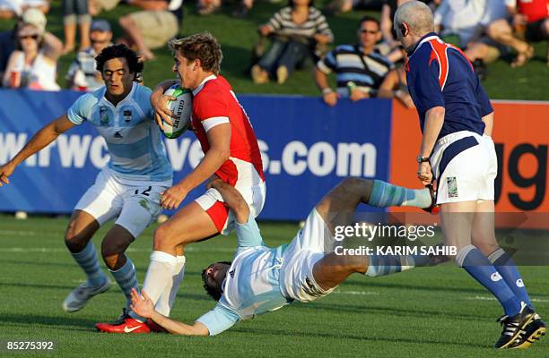 Aled Brew of Wales vies with Martin Buston Moyano and Lucio Lopez Fleming of Argentina during their match on the second day of the Dubai Rugby Sevens...