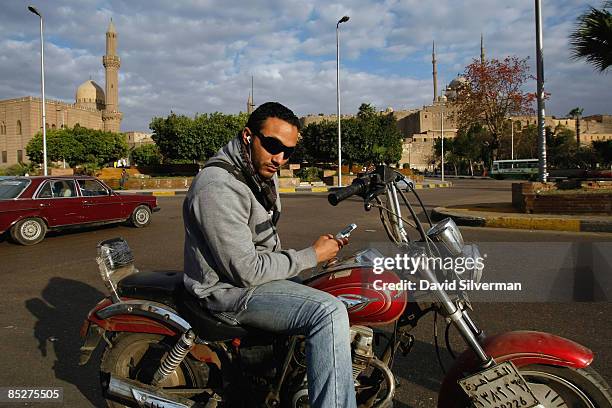 An Egyptian motorbike rider stops to use his mobile phone in Salah ad-Din Square, a central roundabout below the Citadel with its landmark Ottoman...