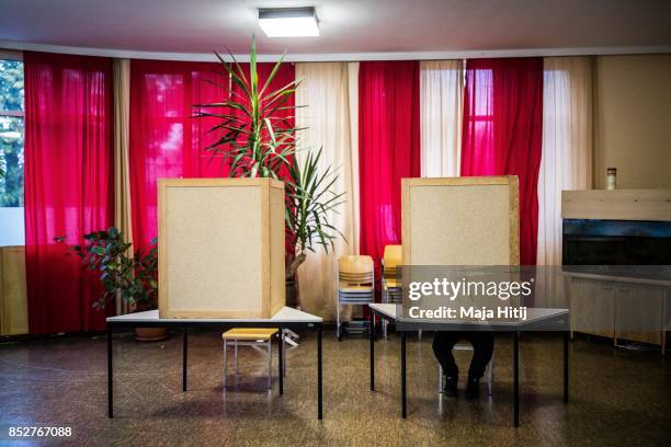 Man sits behind voting booths as he fill in their election ballots at a polling station during German federal elections on September 24, 2017 in...