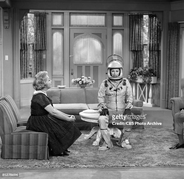 American actress and comedienne Lucille Ball , as Lucille Carmichael, sits on a coffee table, uncomfortably dressed in a spacesuit, while Vivian...