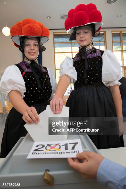 Christina Lehmann and Jana Bruestle wear traditional dresses of the Black Forest area including the typical "Bollenhut" pompon hats as they cast...