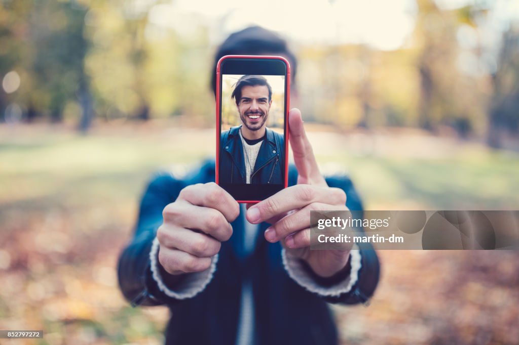 Junger Mann zeigt Selfie zur Kamera