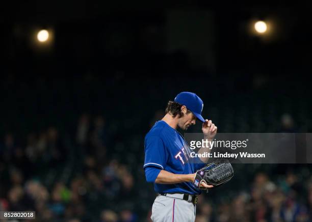 Cole Hamels of the Texas Rangers adjusts his hat as he prepares for a pitch against the Seattle Mariners at Safeco Field on September 21, 2017 in...