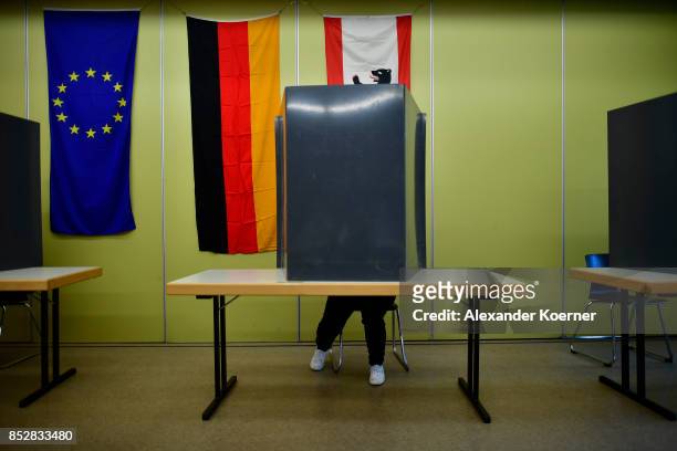 Woman sits behind voting booths as she fills in her election ballots at a polling station during German federal elections on September 24, 2017 in...