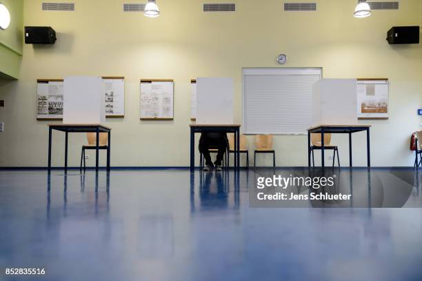 Person seated behind voting booths as they fill in their election ballots at a polling station during German federal elections on September 24, 2017...