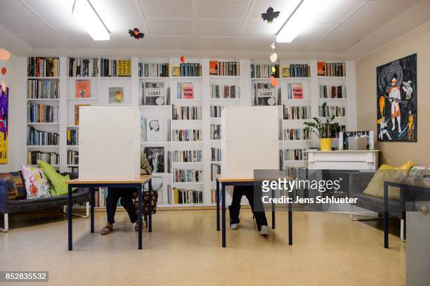 People sit behind voting booths as they fill in their election ballots at a polling station during German federal elections on September 24, 2017 in...