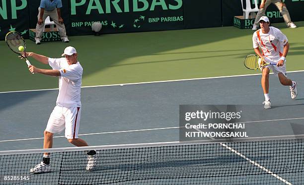 Australia tennis players Chris Guccione hits the ball as he returns to Sanchai and Sonchat Ratiwatana of Thailand while Carsten Ball looks on during...