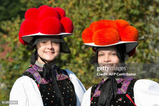 Christina Lehmann and Jana Bruestle pose in traditional dresses of the Black Forest region with the red Bollenhut in Gutach, southern Germany, on...