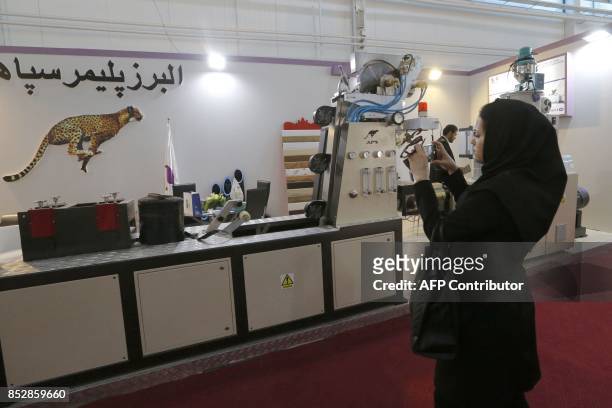 General view shows a woman taking a photo during the Iran-Plast international exhibition in Tehran, on September 24, 2017. / AFP PHOTO / ATTA KENARE