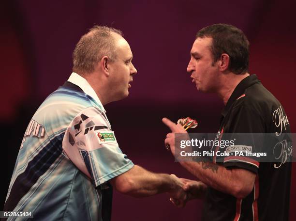 Ian White on the left shakes hands with Richie Burnet after winning in the Third round during day twelve of The Ladbrokes World Darts Championship at...