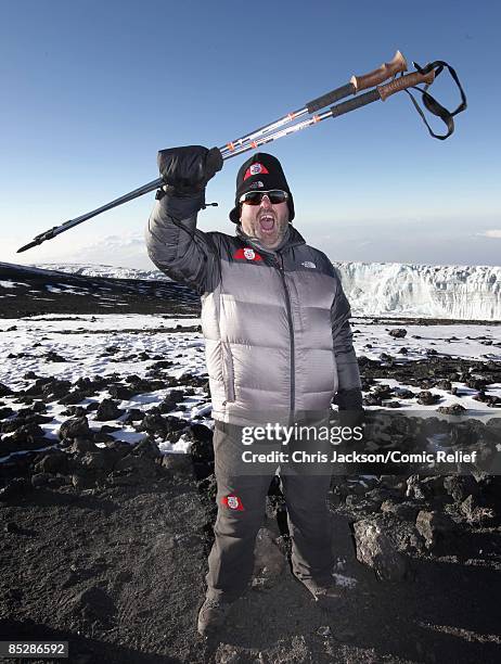 Radio One DJ Chris Moyles holds up his walking poles as he reaches the top of Mount Kilimanjaro on the seventh day of The BT Red Nose Climb of...