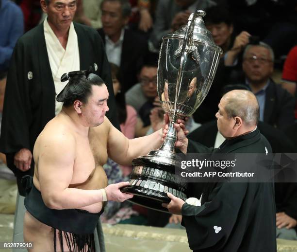 Mongolian yokozuna, or grand champion, Harumafuji receives the championship trophy during the awards ceremony following his victory on the final day...