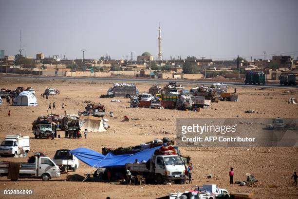 Syrians from the eastern city of Deir Ezzor, who were displaced by the war against the Islamic State group, are seen gathered outside the Ain Issa...