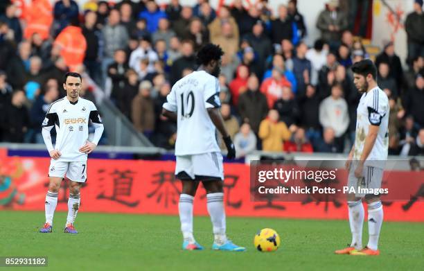 Swansea City's Alejandro Pozuelo , Leon Britton and Wilfried Bony stand dejected waiting to restart the match after Tottenham Hotspur's Emmanuel...