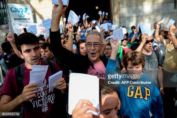 Pro-referendum demonstrators brandish their ballots during a demonstration outside Barcelona's university in Barcelona on September 24, 2017. Spain's...