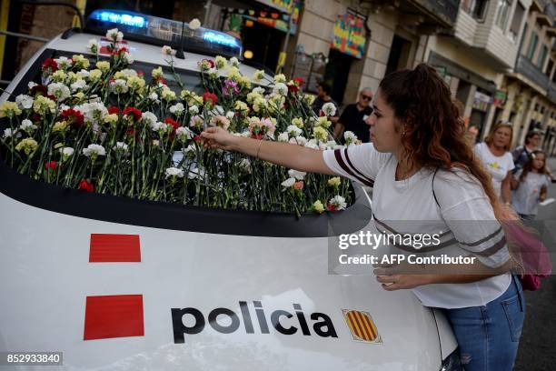 Woman displays a flower on the windshield of a vehicle of Catalan police, known as Mossos d'Esquadra during a pro-referendum concentration in...