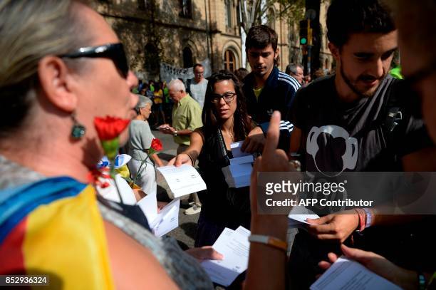 Pro-referendum demonstrators distribute ballots to passer-by during a demonstration outside Barcelona's university in Barcelona on September 24,...