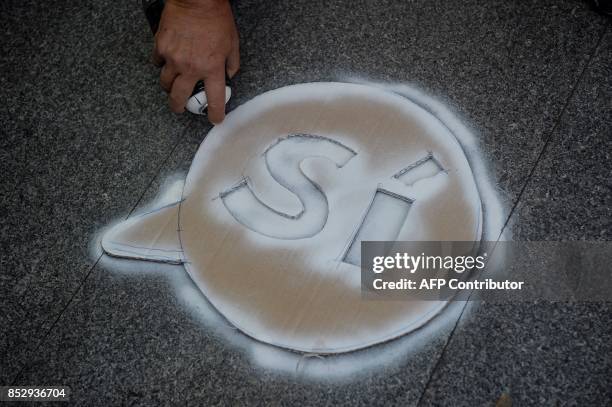 Pro-referendum demonstrator paints a "Yes" on the ground during a demonstration outside Barcelona's university in Barcelona on September 24, 2017....