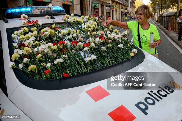 Woman displays a flower on the windshield of a vehicle of Catalan police, known as Mossos d'Esquadra during a pro-referendum concentration in...