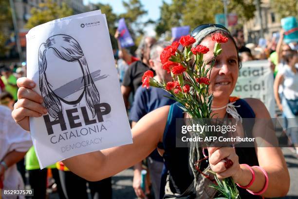 Pro-referendum demonstrator holds flowers and a placard during a demonstration outside Barcelona's university in Barcelona on September 24, 2017....