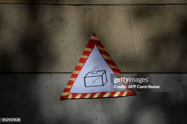 Picture taken on September 24, 2017 shows a poster depicting a ballot-box in a triangle stuck on a wall during a pro-referendum demonstration outside...