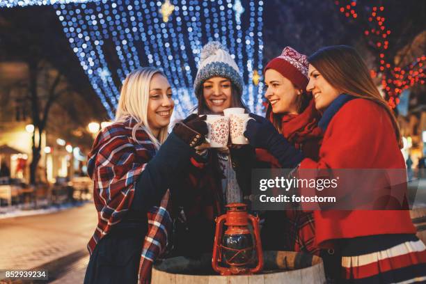 friends cheering on a street decorated with christmas lights - mulled wine stock pictures, royalty-free photos & images