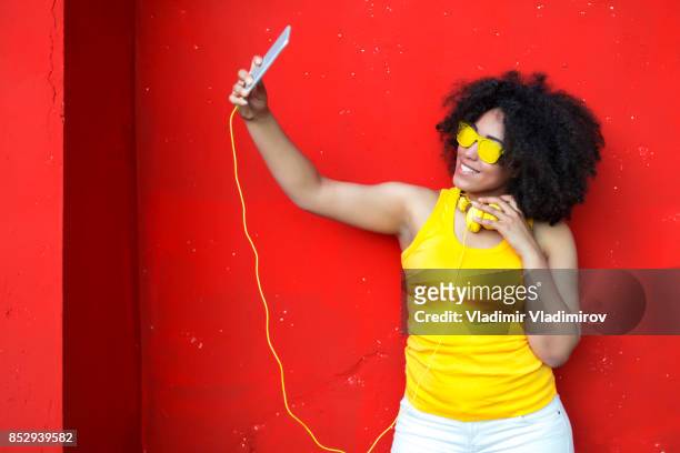 vrouw met gele zonnebril selfie te nemen - fashion pretty woman listening music in headphones with smartphone colorful stockfoto's en -beelden