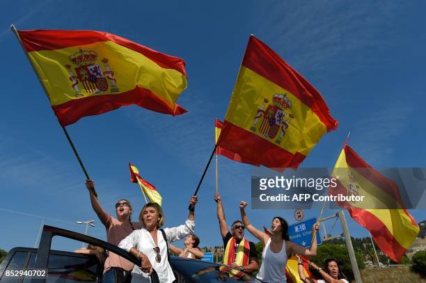 People wave Spanish flags as they gather at Barcelona's port bringing food and drinks to Spanish National Police and Guardia Civil officers, who are...
