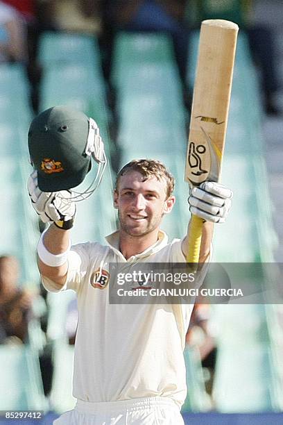 Australian batsman Phillip Hughes raises his bat and helmet as he celebrates after scoring his century, the second one of the Test, on March 8, 2009...