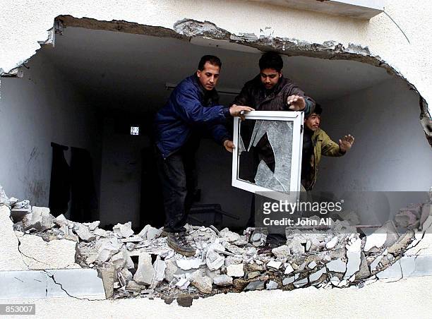 Palestinians carry rubble out through the remains of a wall of their house February 4, 2001 near the settlement of Netzarim in the Gaza Strip where...