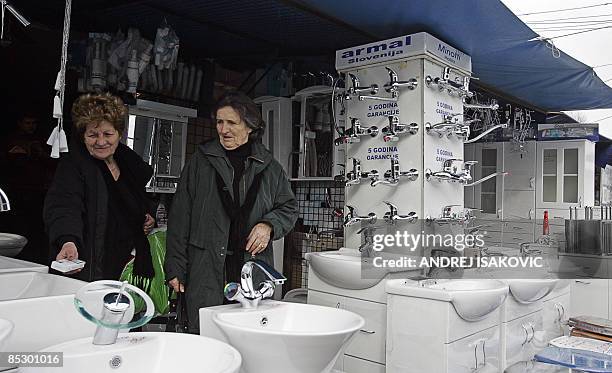 By Aleksandra Niksic - Two women inspect some bathroom accessories at the Belgrade flea market on March 6, 2009. Despite warnings of a looming...