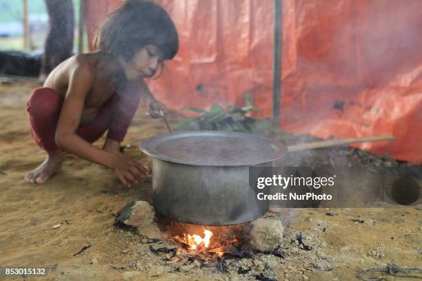 Rohingya girl is cooking at a refugee camp in Ukhia, Bangladesh on September 23, 2017. About 430,000 Rohingya people have fleeing violence erupted in...