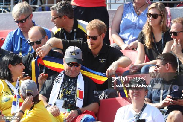 Prince Harry puts the Romanian flag scarf on the man in front of him as he watches the Athletics during Day 2 of the Invictus Games 2017 at York...