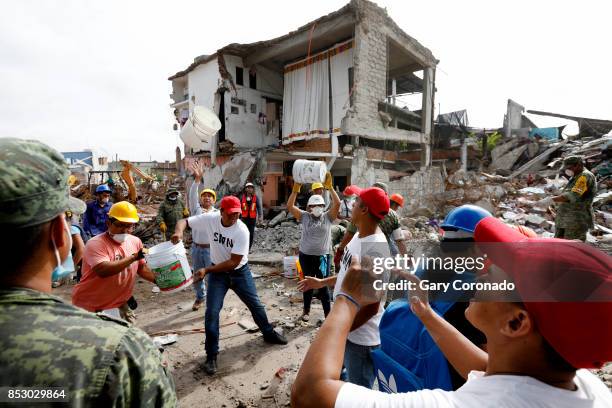 Volunteers along side the Mexican Military remove rubble beginning the reconstruction process where a block of homes were destroyed by the recent...