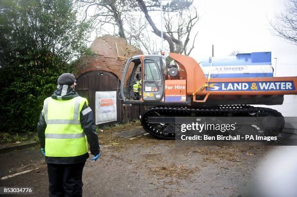 Volunteers knock down a wall which may collapse in Burrowbridge, Somerset, as heavy rain and storms look set to cause further significant flooding.
