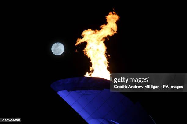 The moon is seen behind the Olympic flame at the 2014 Sochi Olympic Games in Sochi, Russia.