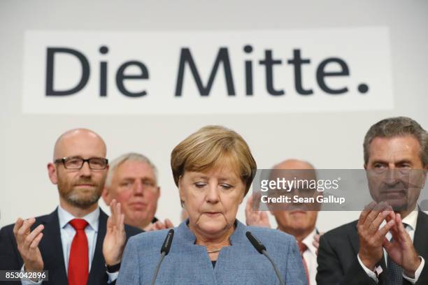 German Chancellor and Christian Democrat Angela Merkel speaks to supporters while standing next to leading members of her party following initial...